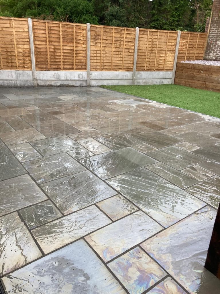 Paved garden patio with lawn, raised edging and timber fencing